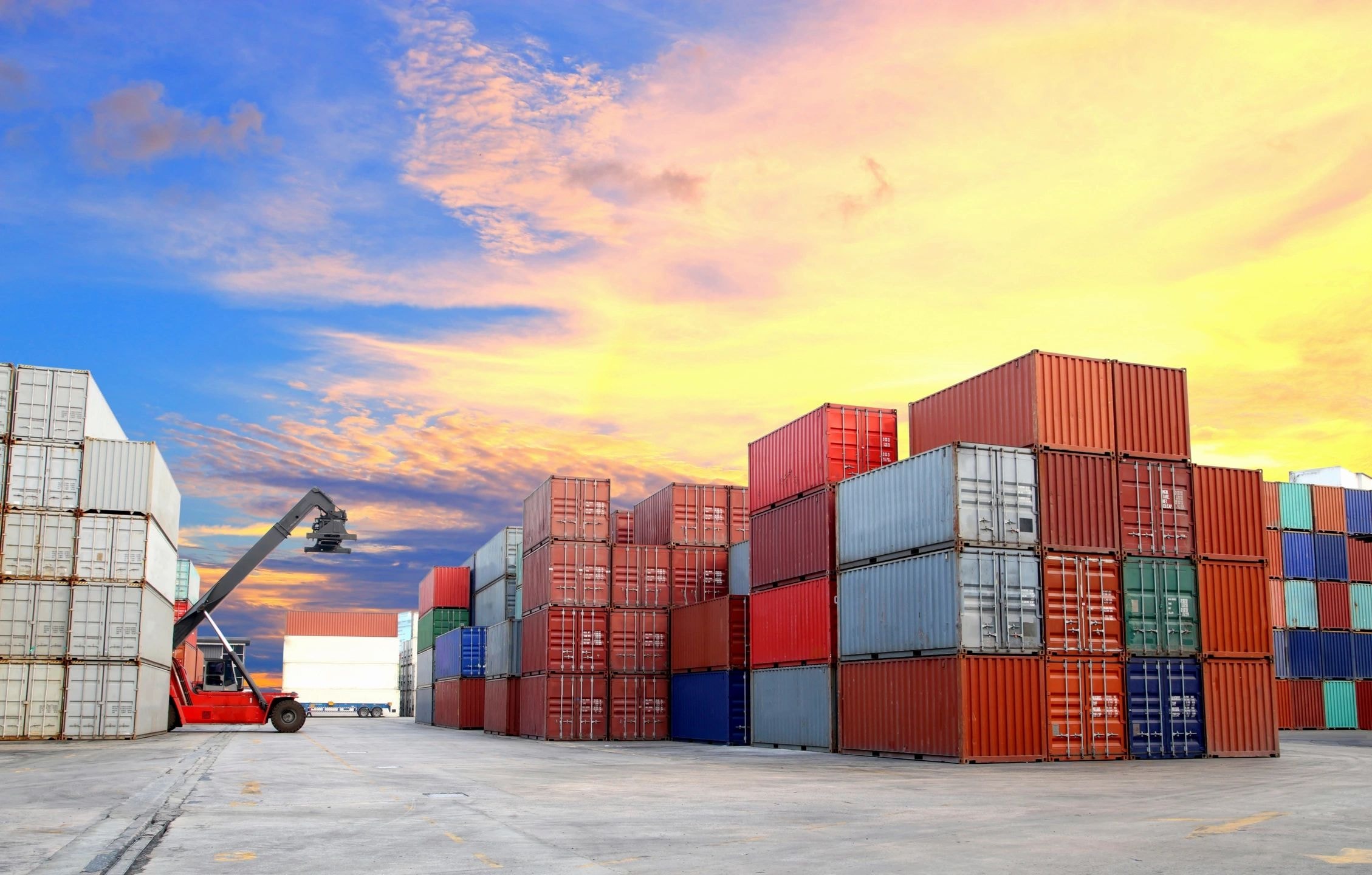 Industrial port with shipping containers at sunset